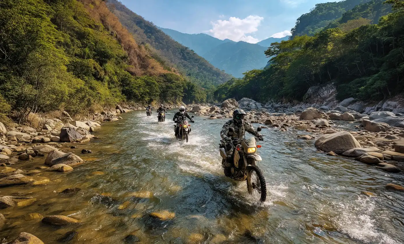Enduro riders crossing a rocky river between green mountains in Mexico